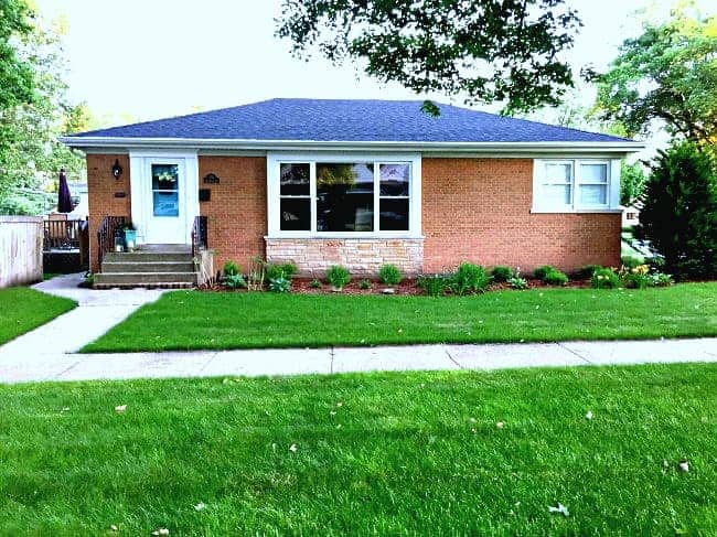 A large lawn in front of a brick house