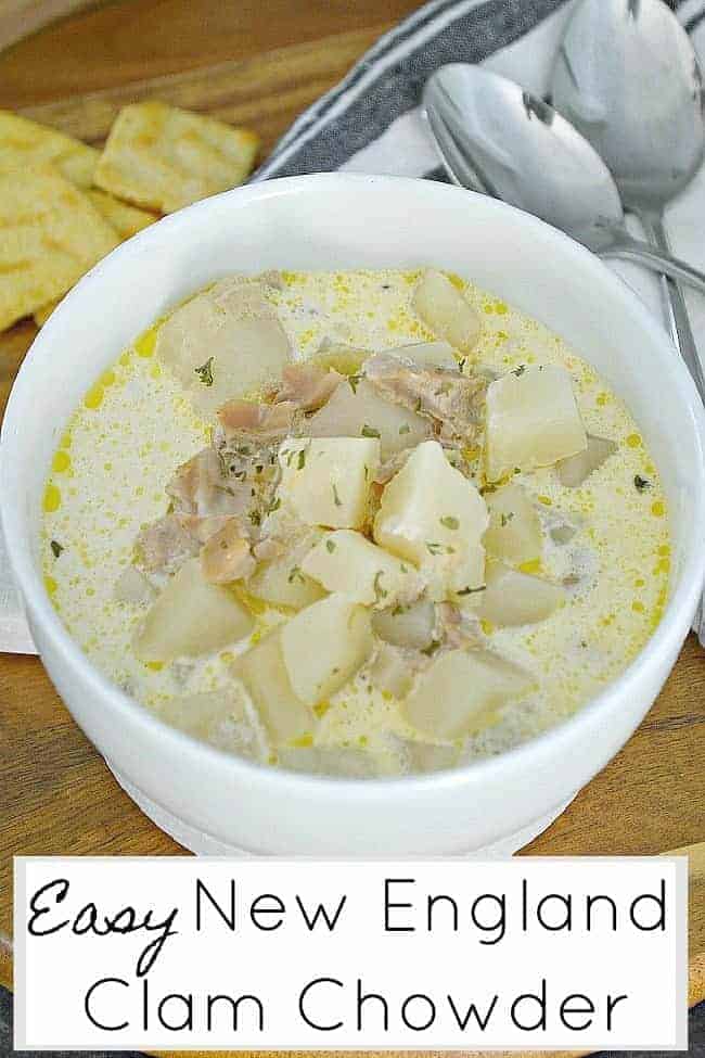 bowl of easy New England Clam Chowder sitting on wood cutting board with 2 spoons and crackers.