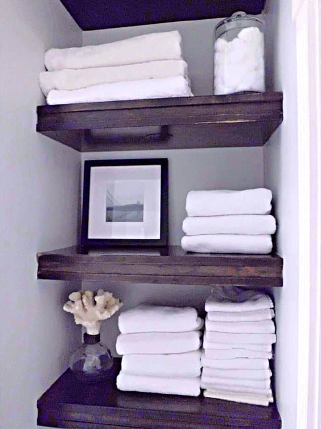 wood bathroom shelves with white towels on them