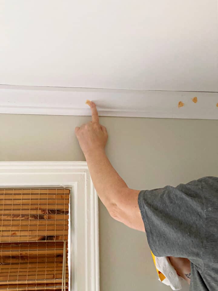 applying wood putyy to nail holes in crown molding