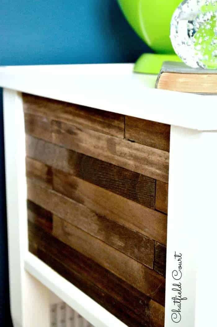 stained paint sticks on the side of a white wood nightstand