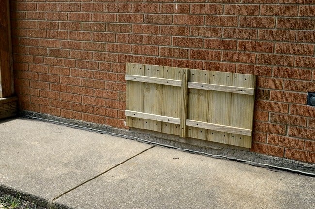 untreated DIY wood shutter on brick house