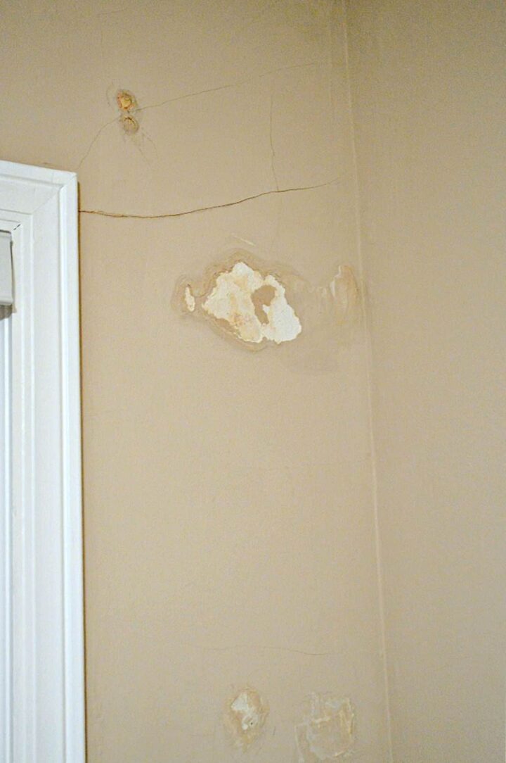 cracks and water damage on plaster wall by window