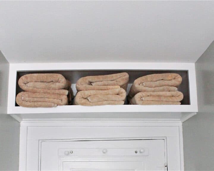 folded towels in cabinet above bathroom door