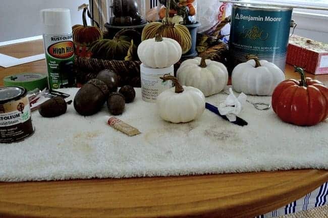 paint supplies and mini faux pumpkins on towel on dining table