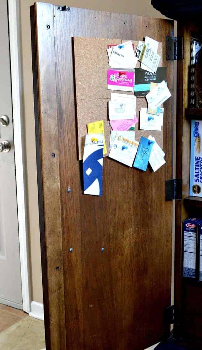 inside of kitchen cabinet with cork board and business cards