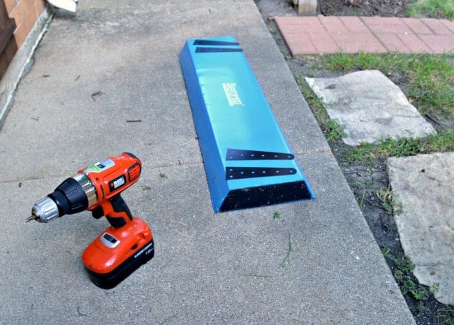 drill and kneeling pad on sidewalk with homemade hinges