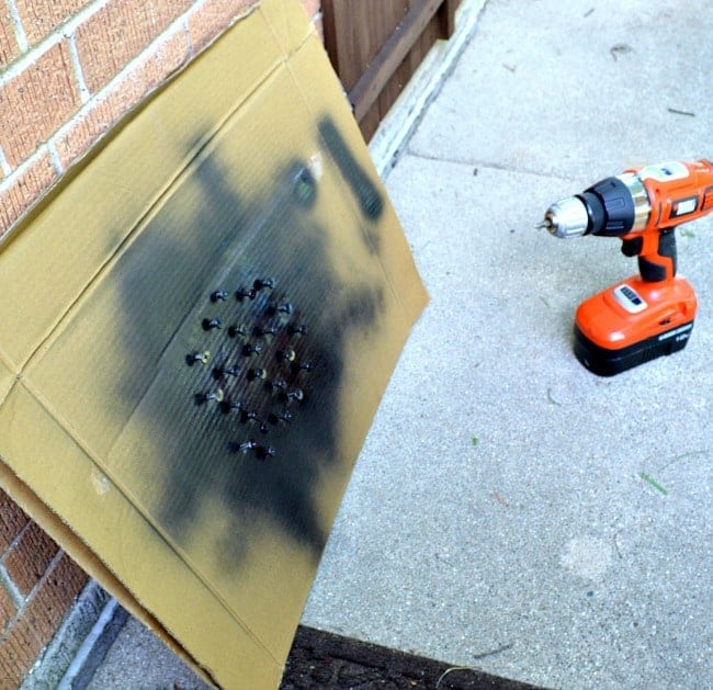 black spray painted screws in cardboard and drill on sidewalk