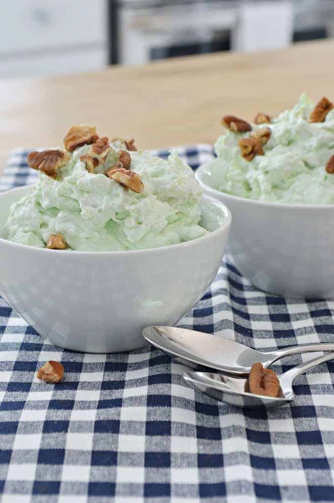 green stuff in white bowl sprinkled with chopped pecans 