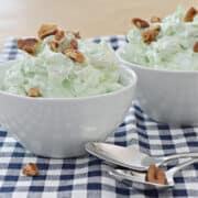 green stuff in small white bowl with nuts on top