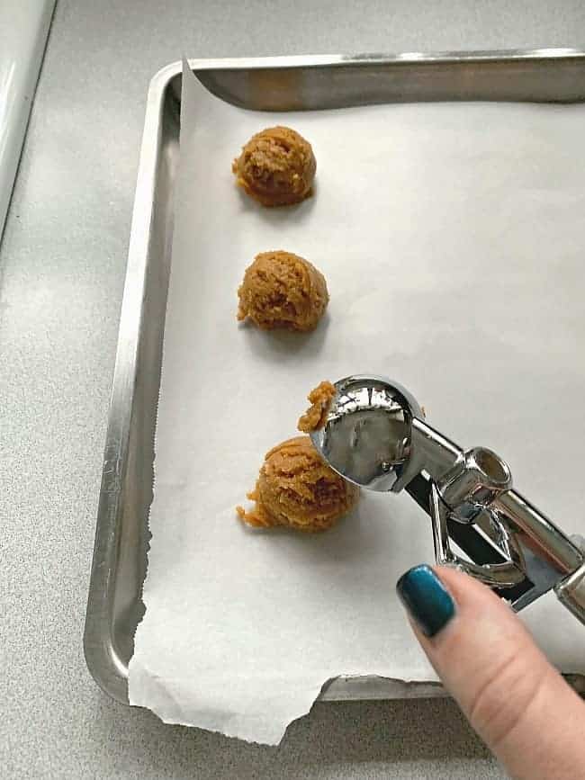 scooping peanut butter cookie batter onto parchment paper