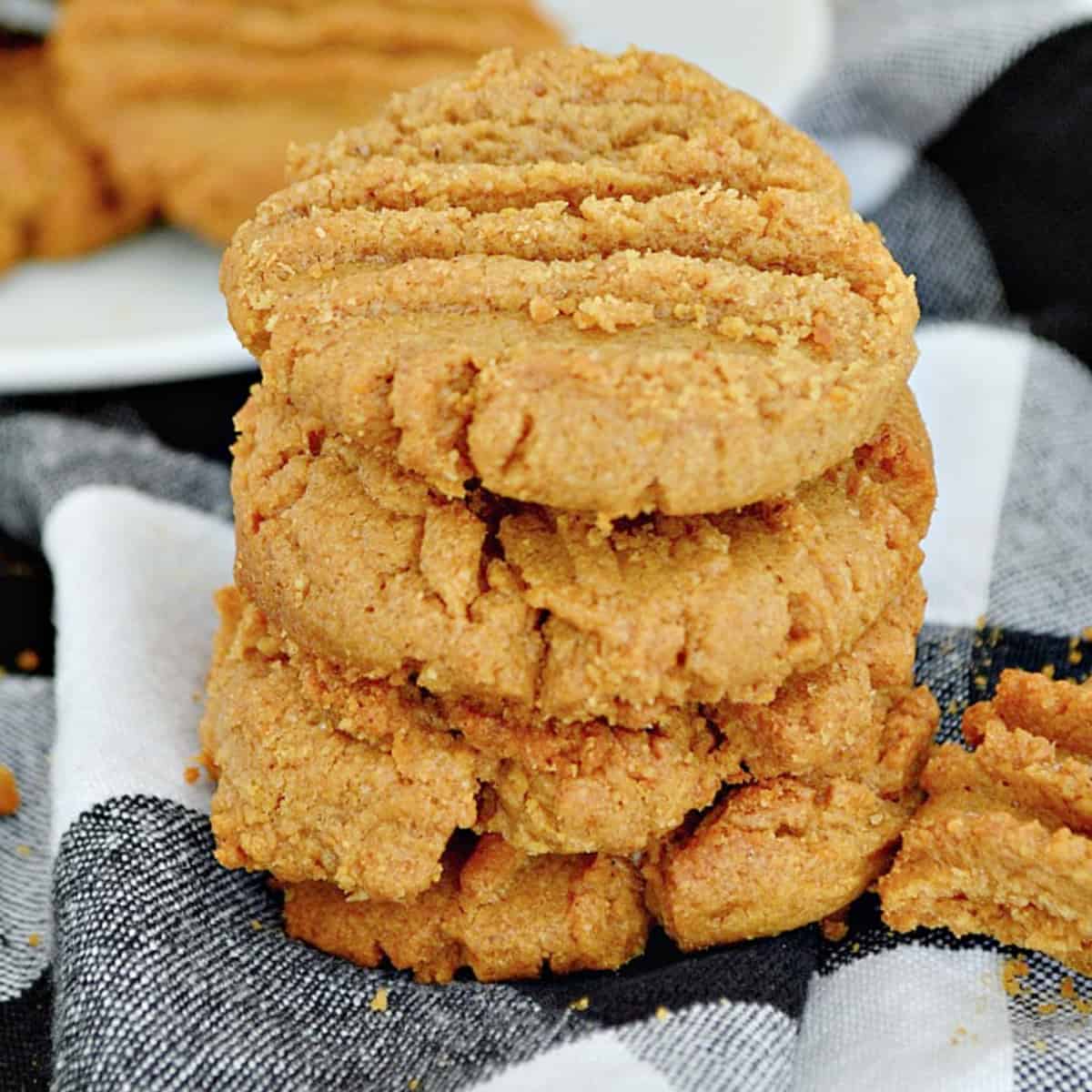 4 peanut butter cookies stacked on top of each other on checked towel