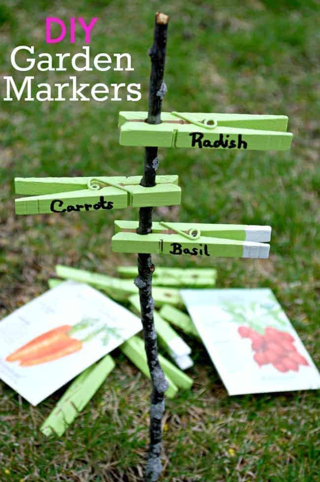 DIY garden markers on a stick in the grass with seed packets next to it