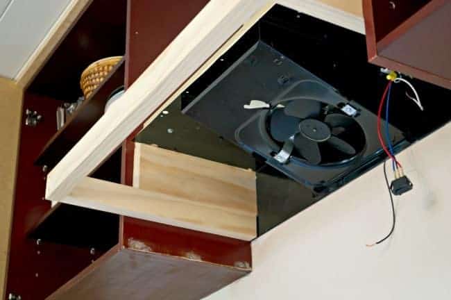 underside view of wood frame of DIY range hood with repurposed fan 