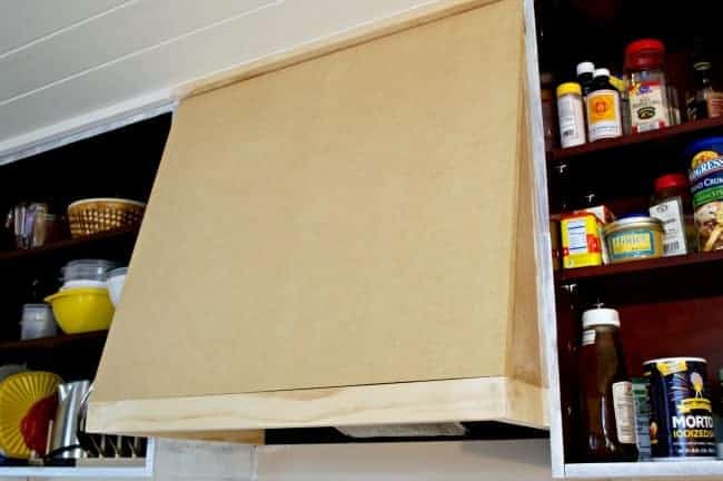 wood panels in place on a DIY custom range hood between two cabinets without doors