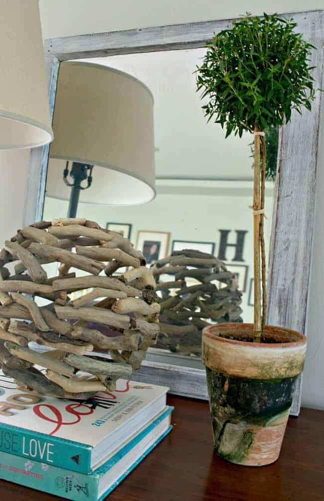 painted old window turned into a mirror with a potted topiary and stacked books