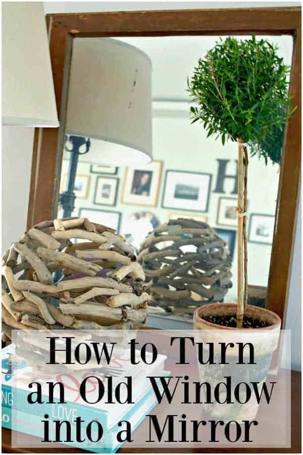 old window turned mirror on a cabinet with potted topiary and stacked books