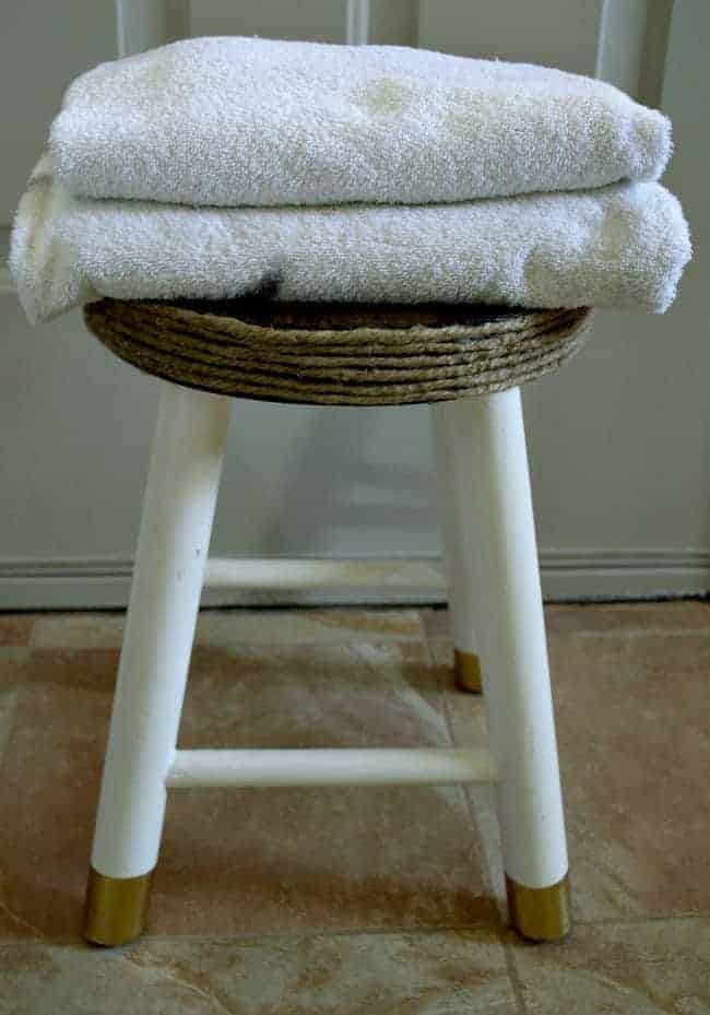 2 white bath towels on top of a small white stool