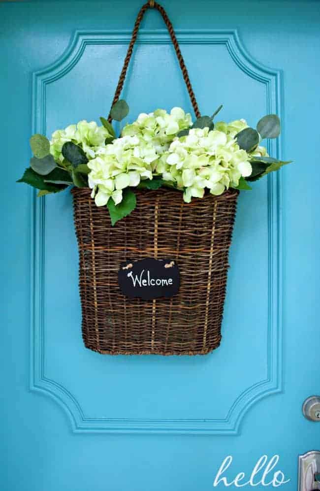 hanging basket with faux hydrangeas on a turquoise front door