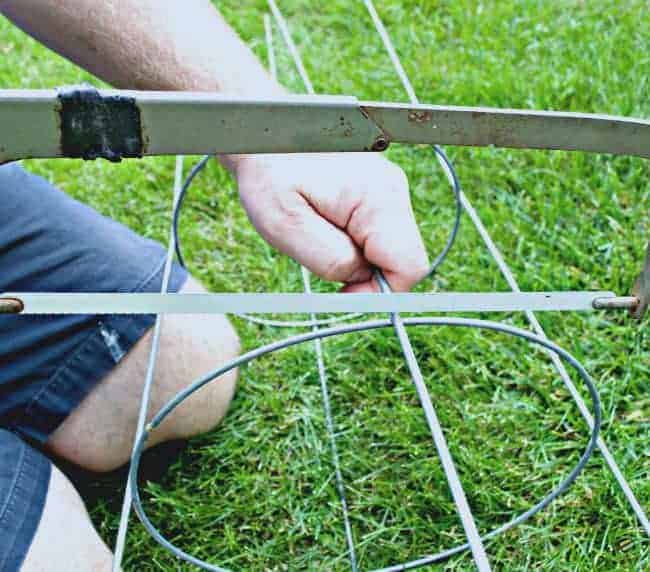 using a hack saw to cut off legs on tomato cage