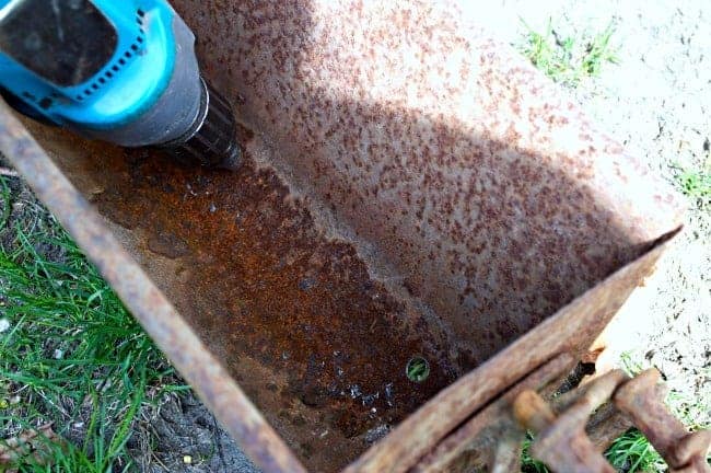 drilling holes in rusty old corn crib box
