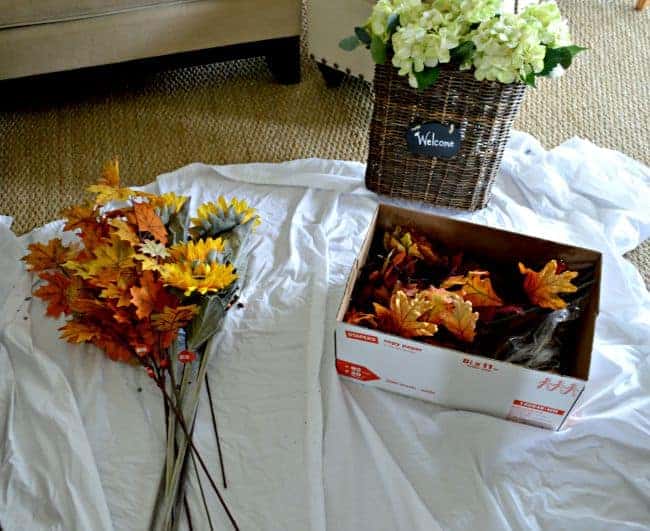 faux leaves and flowers laying on a sheet for a fall front door basket wreath