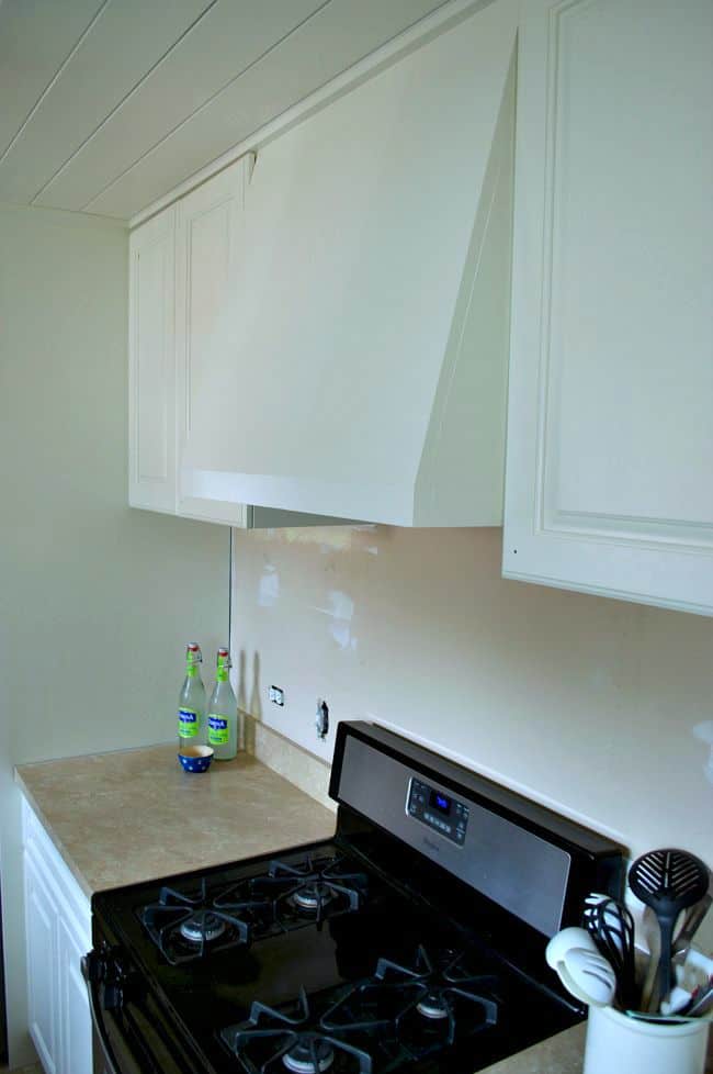 white painted upper kitchen cabinets and custom stove hood
