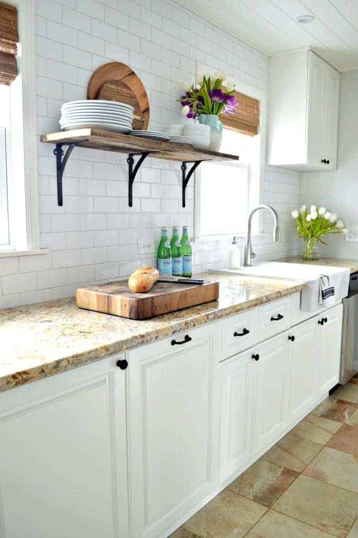 white galley kitchen with subway tile backsplash and granite countertops