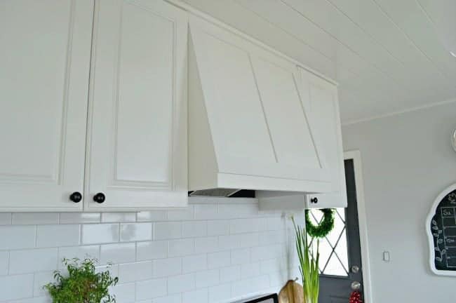 side view of custom range hood and white subway tile backsplash