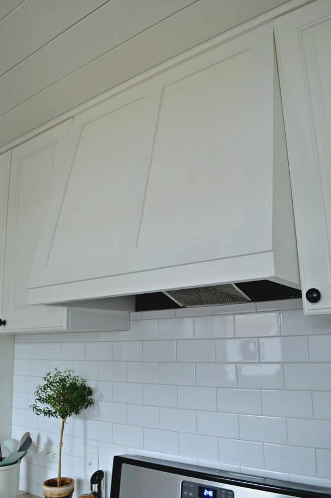 white subway tile backsplash and white kitchen stove hood