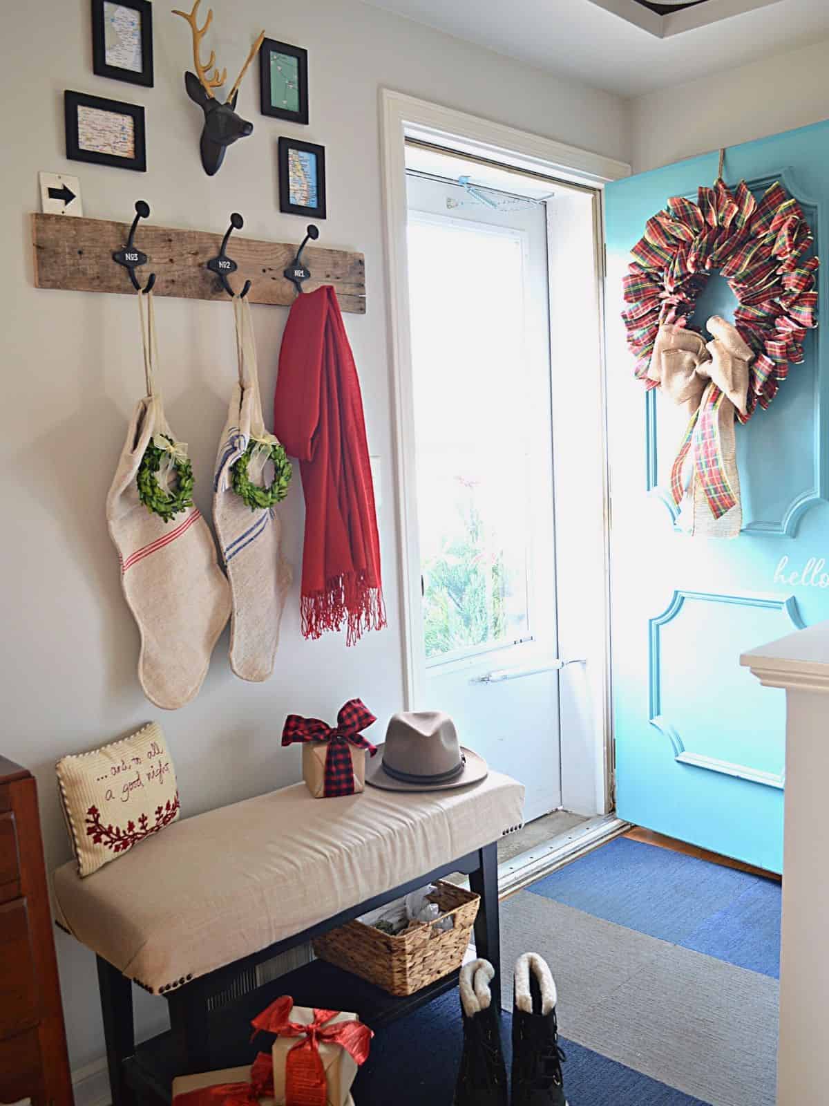 DIY ribbon wreath hanging on turquoise front door in small entryway