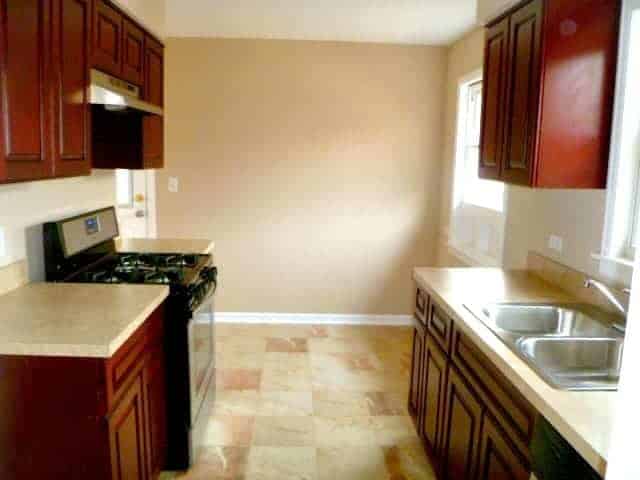 galley kitchen with cherry cabinets and brown tile floor