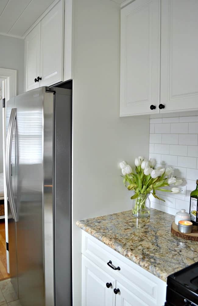 painted white cabinet built around stainless steel refrigerator