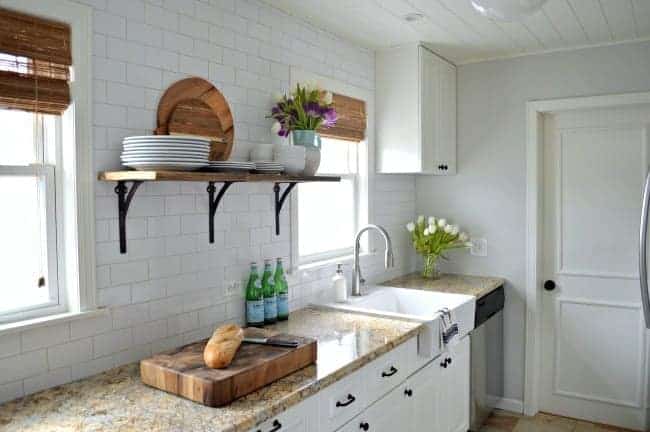 barn wood shelf and white kitchen cabinets with granite countertop