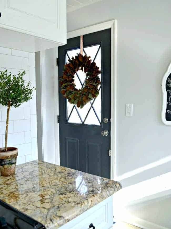 dark gray painted kitchen back door with magnolia wreath hanging on it