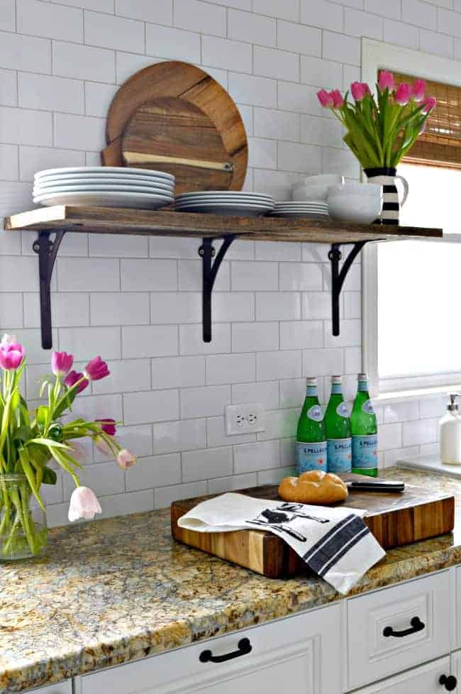 barnwood kitchen shelf with white plates on it with chunky wood cutting board on a countertop