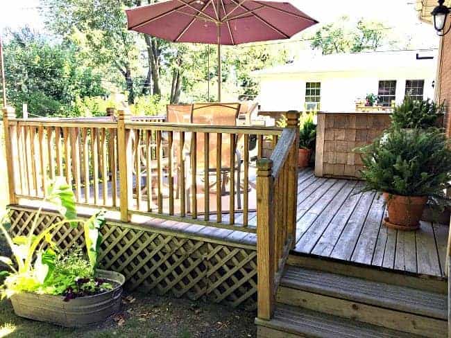 backyard deck with table, chairs and burgundy umbrella