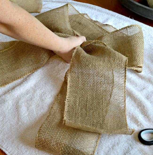 hand gathering burlap bow in the center