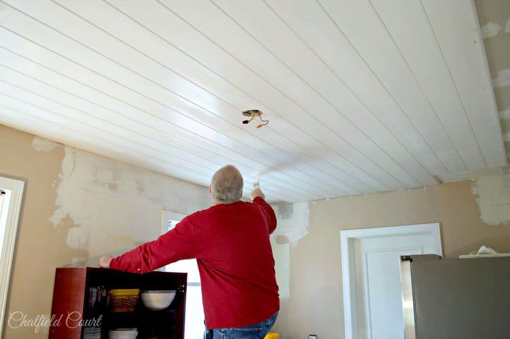 man painting tongue and groove ceiling