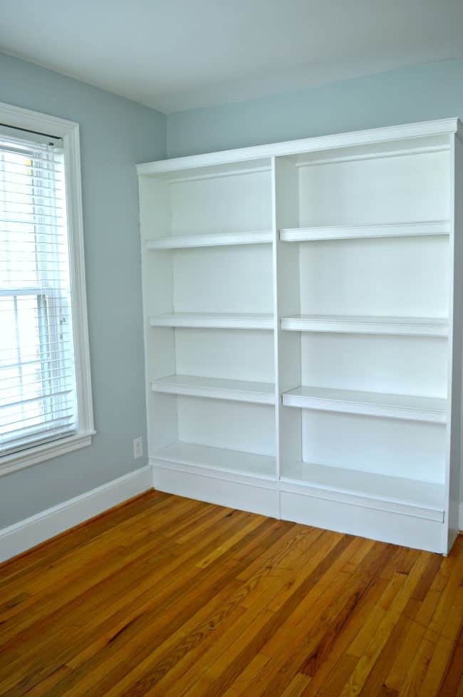 empty white bookcase in guest bedroom painted light blue