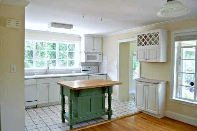 Green butcher block kitchen island in the center of white kitchen