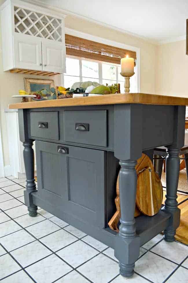 side view of gray kitchen island with cutting boards on side shelf