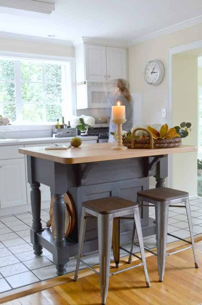 kitchen island painted gray with candle and woven tray on top of butcher block