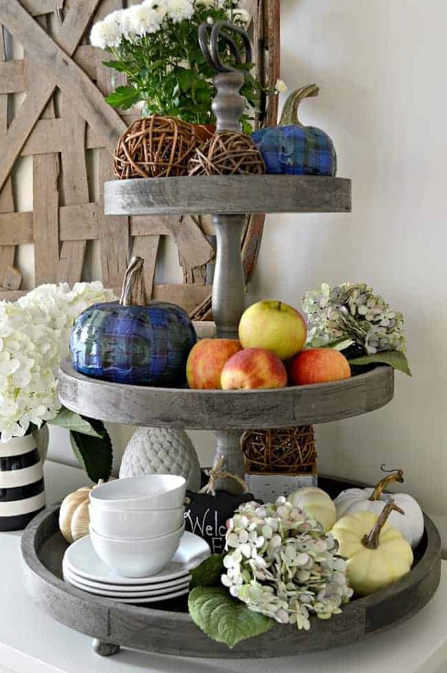 blue plaid pumpkins on 2 level tray with apples, dishes and other fall decor