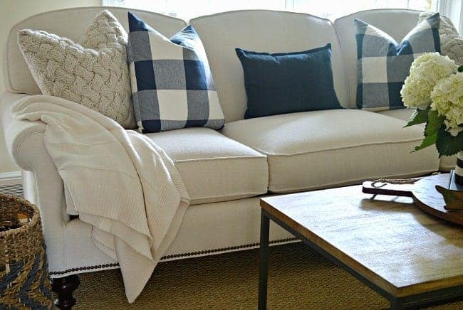 new white couch in living room with navy checked and knitted pillows