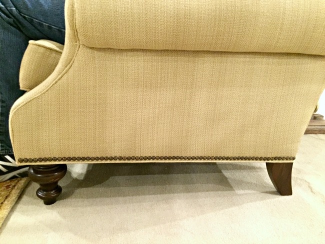 the side view of a new sofa with wood legs and upholstery tacks 
