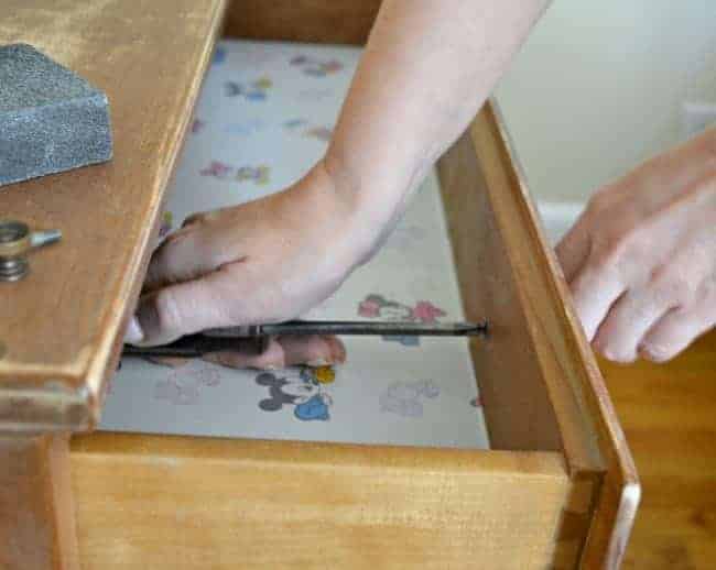 removing hardware in top dresser drawer with a screwdriver