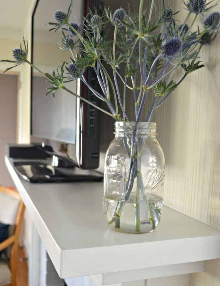 jar of flowers on fireplace mantel