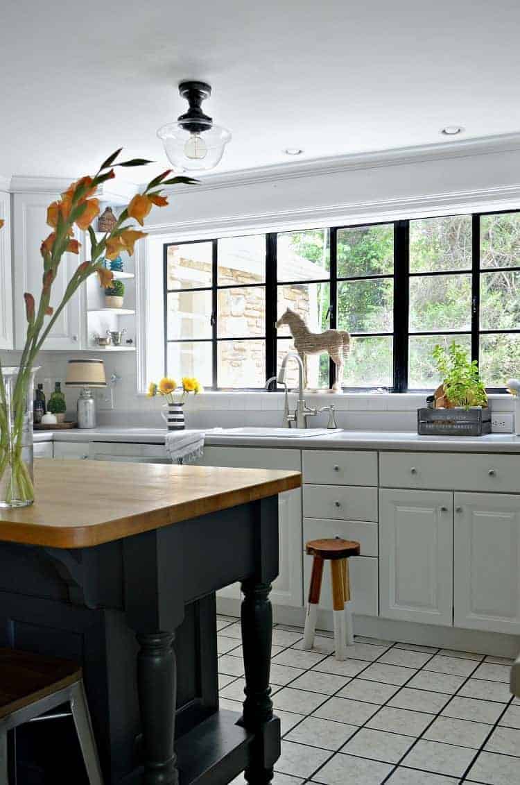 small white kitchen with island and large window