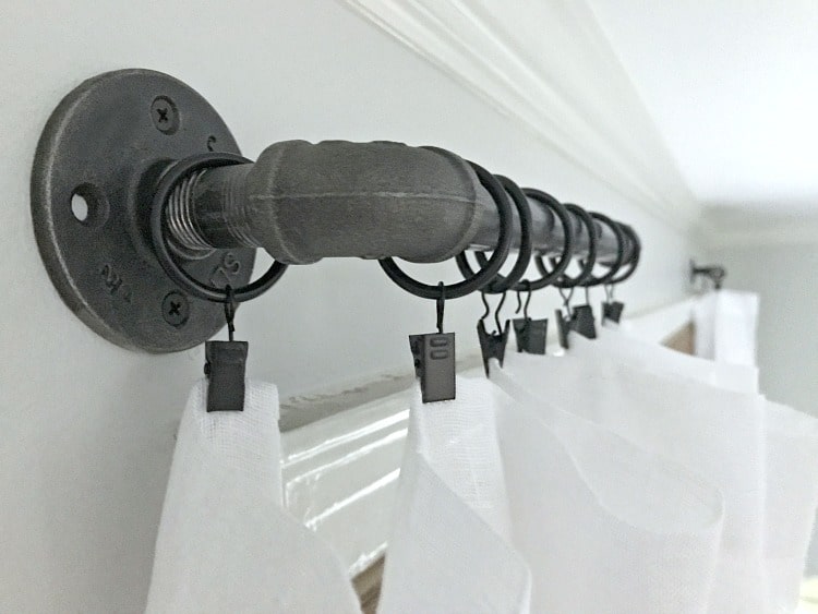 pipe hanging on wall with curtain rings and curtain